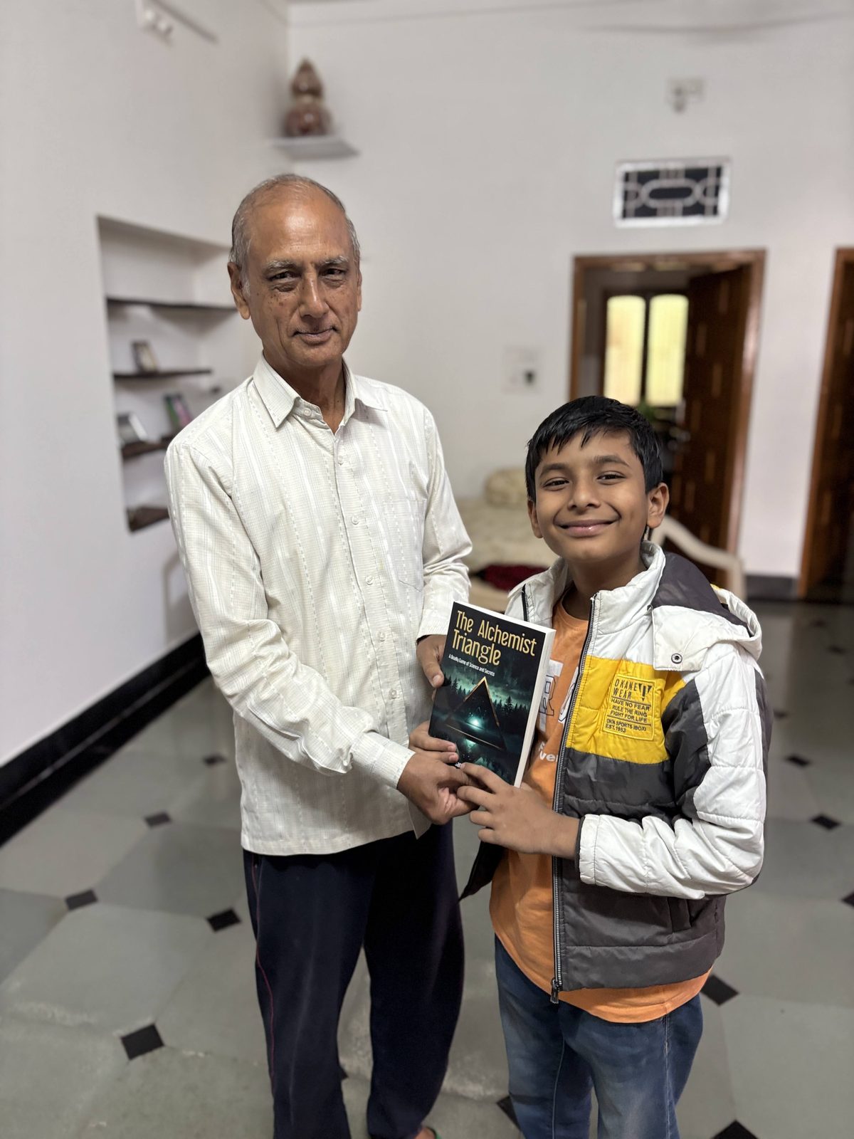 Two generations of Sandeep Jain's family holding a copy of The Alchemist Triangle
