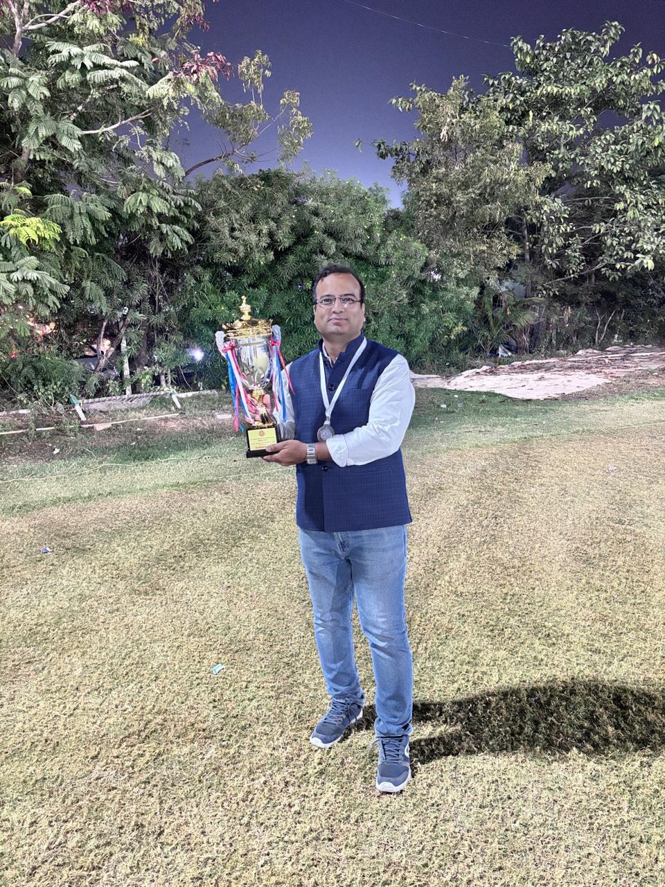 Sandeep Jain with a Runner-Up trophy, outdoor evening event